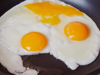 Scrambled eggs in an iron pan on the rustic wooden table