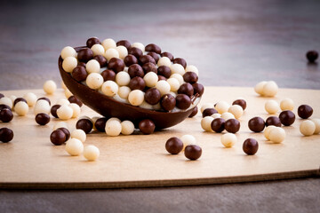 Mini stuffed easter egg with white and black chocolate balls on the top and around on a wooden table.