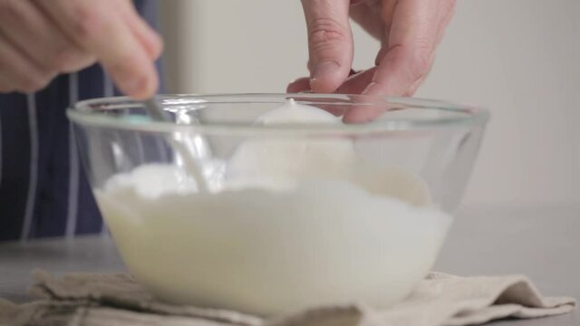 Male hands mixing cream with a spoon inside a glass bowl