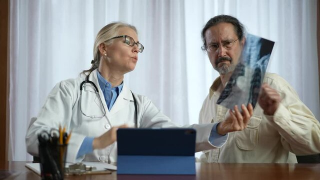 Doctor is shows X-ray images to patient. Concept of doctor discuss personal healthcare solutions.