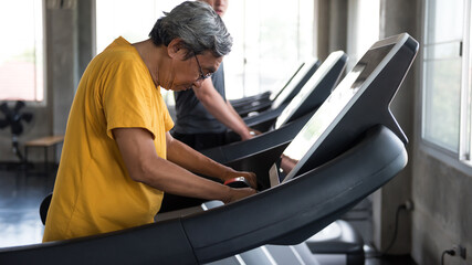 Fototapeta na wymiar Old Asian man walk on treadmills of fitness gym