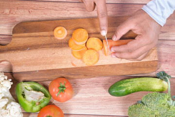 cutting fresh carrots on chopping board on table 