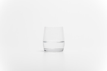 The half full glass of pure water isolated on a white background. A drinking glass half filled with water. A half empty glass with water.