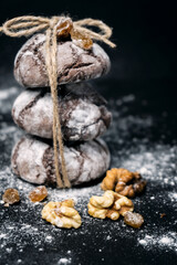 Chocolate cookie with nuts and flour. Chocolate chip cookie on black background with copy space for text, closeup. vertical photo