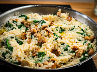 Risotto with champignons and spinach cooking in frying pan 