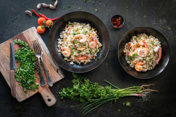Asian fried rice with shrimp on the black dish in Thai. Prepared in wok. Top view.