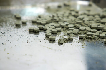 Pills broken in metal plate. Drugs quality check in laboratory background.
