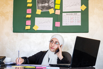Muslim women working in the office from home using laptop and mo