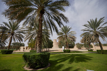 Fototapeta na wymiar A view to the 'wedding cake' - like tower in Al Jahili Fort, in Al Ain, UAE, seen from a Palm Tree Park