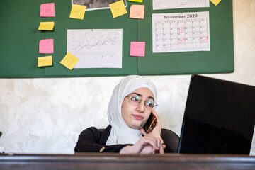 Muslim women working in the office from home using laptop and mo