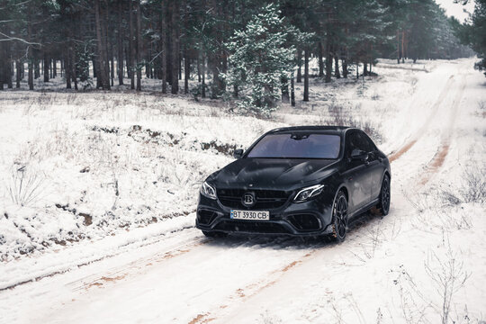 Kherson, Ukraine - February 2021. Powerful Mercedes-AMG E63S Brabus 800 in a matte black color in the winter snowy forest.