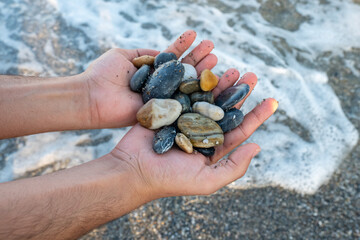 Stones in male's hands near the ocean