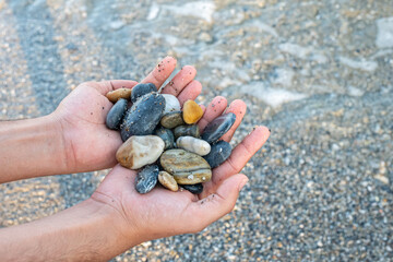 Stones in male's hands near the ocean