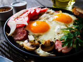 Sunny side up eggs with spinach, toasted bread and sausages on wooden table
