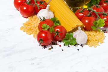 spaghetti, fresh tomatoes and spices on a white background, top view