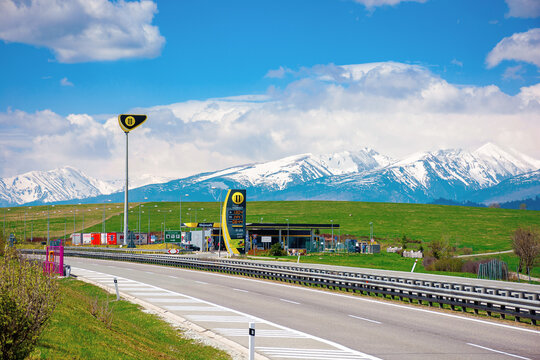 strba, slovakia - 01 MAY 2019: slovnaft gas station on a freeway. sunny scenery with green meadows beneath a blue sky with fluffy clouds. snow capped tatra mountains in the distance. wonderful journey