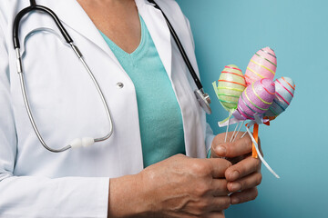 Doctor holding Easter painted eggs in her hands on blue background, medicine