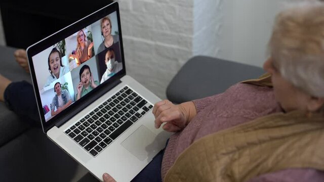 Elderly woman making video call on laptop, waving at screen, chatting with children, free space
