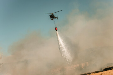 Helicóptero apagando un incendio en el que el fuego crea mucho humo