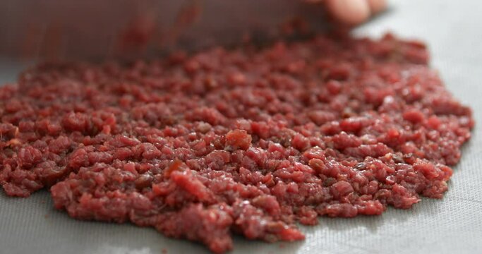 Horse meat finely chopped using sharp knife, preparing Steak Tartare, or minced steak, close-up