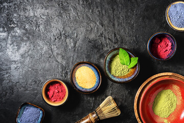 Various matcha tea powders on a dark concrete background with copy space.