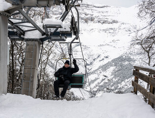 a man in a black jacket on a ski fan cooler in the mountains 