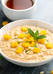 Rice pudding with cinnamon and mango in white bowl