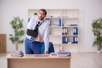 Young arm injured male employee working in the office