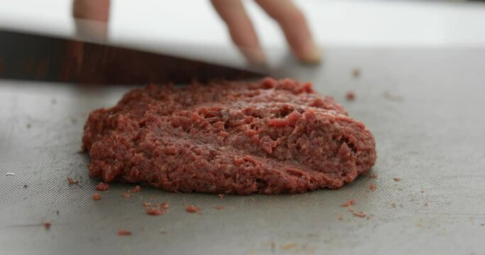Horse meat finely chopped using sharp knife, preparing Steak Tartare, or minced steak, close-up
