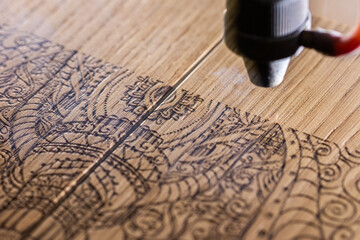 laser engraves the image of an Indian elephant on a wooden surface - 417177598