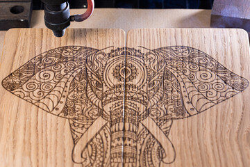 laser engraves the image of an Indian elephant on a wooden surface - 417177734