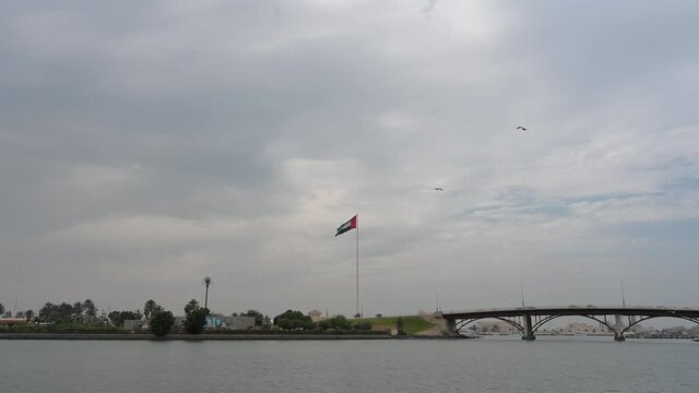 Flag of the United Arab Emirates waving in the air at Sharjah's Flag Island on a cloudy winter day. 4K Footage