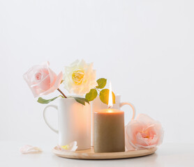 beautiful roses and burning candles on white background