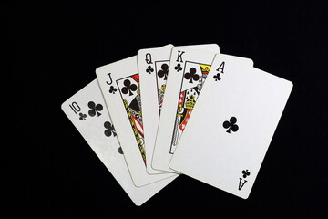royal flush black clubs playing cards on black background