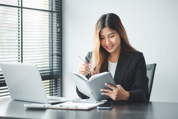 Asian Young business woman working at home with laptop and papers on desk