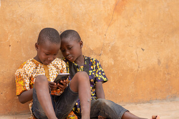 african kids using a smartphone. two african children viewing content on a mobile phone together