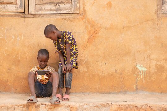 african kids using a smartphone. two african children viewing content on a mobile phone together