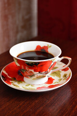 Vintage coffee service with red poppies on the wooden table against the background of dark interior.
