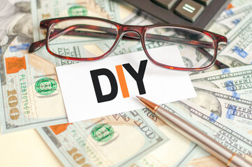The letters DIY are written on a white card lying on the bills, glasses, pen and calculator in the background. The concept of business and Finance