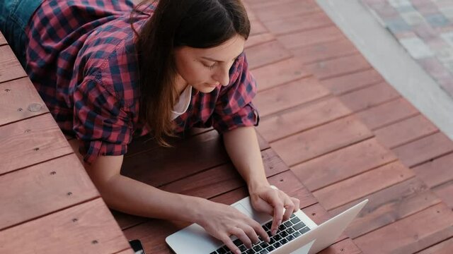 Girl working at a laptop in the fresh air. Satisfied young woman freelance blogger makes entries on her blog