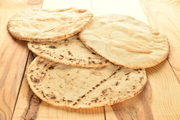 Fresh pita bread, close-up, on a wooden table.