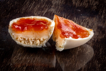 Mini cheese cake easter egg with white chocolate on a class stand on a wooden table.