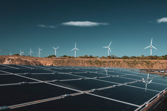 Wind farm and solar panels under a beautiful blue sky with a few clouds. Renewable energy generation for environmental conservation concept.