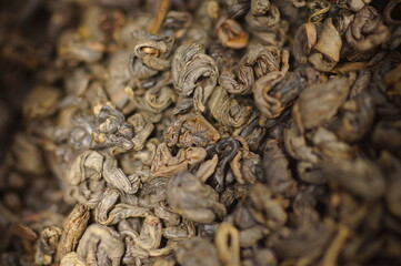 Dried green tea leaves. Preparing a hot drink. Several servings of tea in a zoomed-in view. Tea in a metal tin.