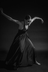 black and white dramatic vintage portrait of a girl, dancing ballerina in a black bodysuit in the Studio on gray background