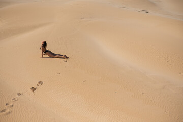 Woman doing yoga stretches on sand dune