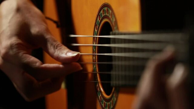 closeup of mans hands playing a classical guitar