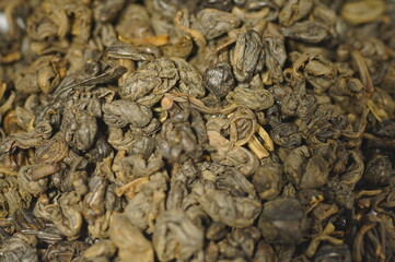 Dried green tea leaves. Preparing a hot drink. Several servings of tea in a zoomed-in view. Tea in a metal tin.