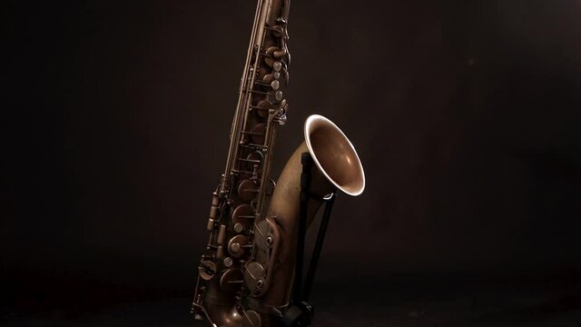 Vintage tenor saxophone on display with dark background, rising medium shot