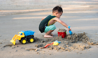 little boy playing with sand on the beach